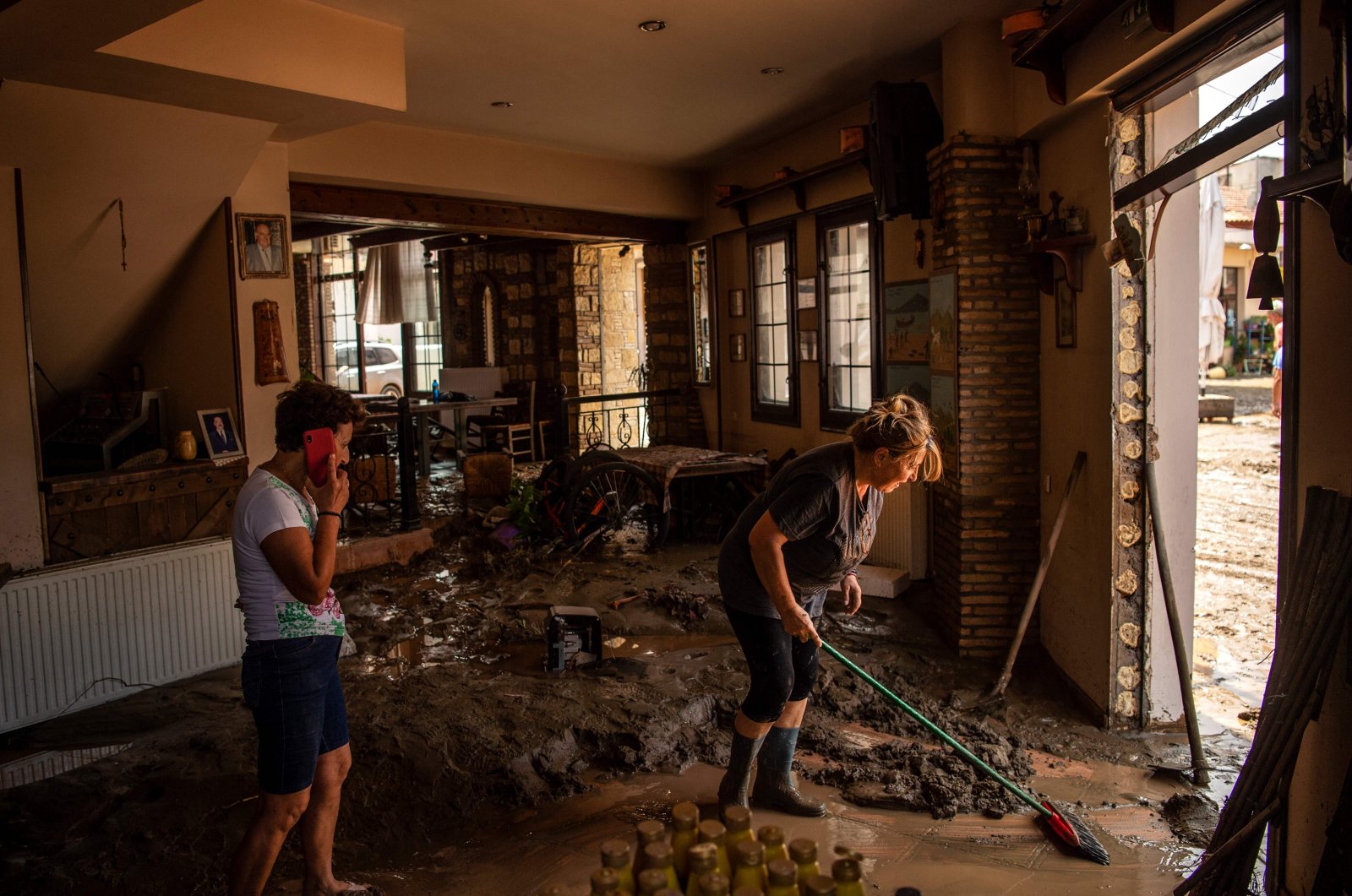People try to move away water and mud from their shop, following a storm at the village of Politika, on Evia island, northeast of Athens, Greece, Aug. 9, 2020. (AFP Photo)
