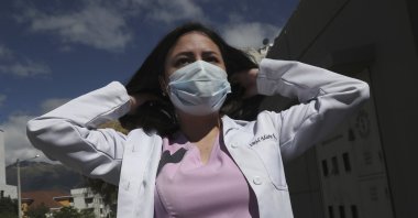 Dr. Maria Jose Casco, 24, adjusts her hair as she walks near her home in Quito, Ecuador, Aug. 5, 2020. A newly qualified doctor, Maria has not found work after graduating in Ecuador in April. (AP Photo)