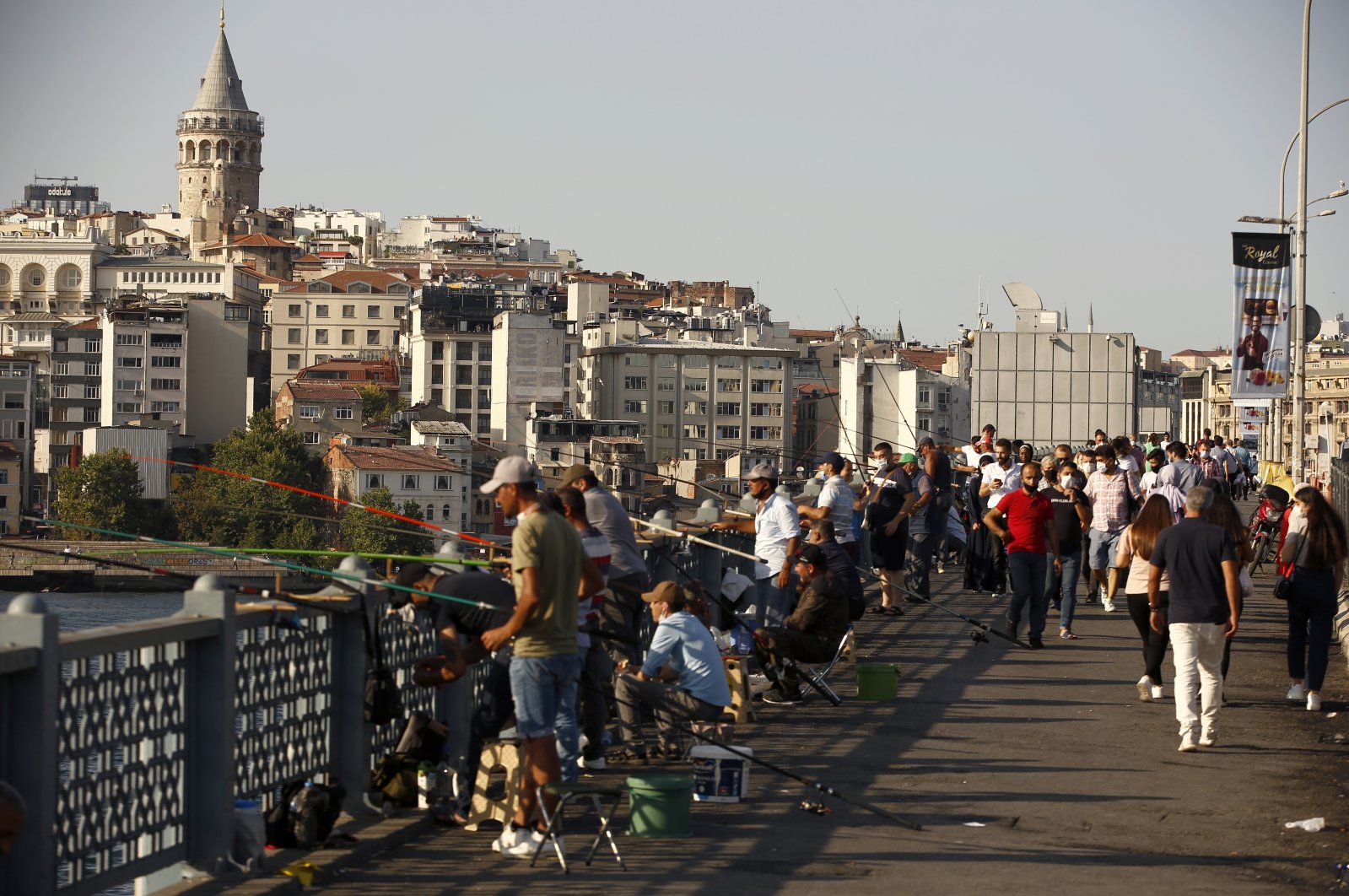 People walk along the Galata Bridge, with the historical Galata Tower in the background, in Istanbul, Turkey, Aug. 7, 2020. (AP Photo)