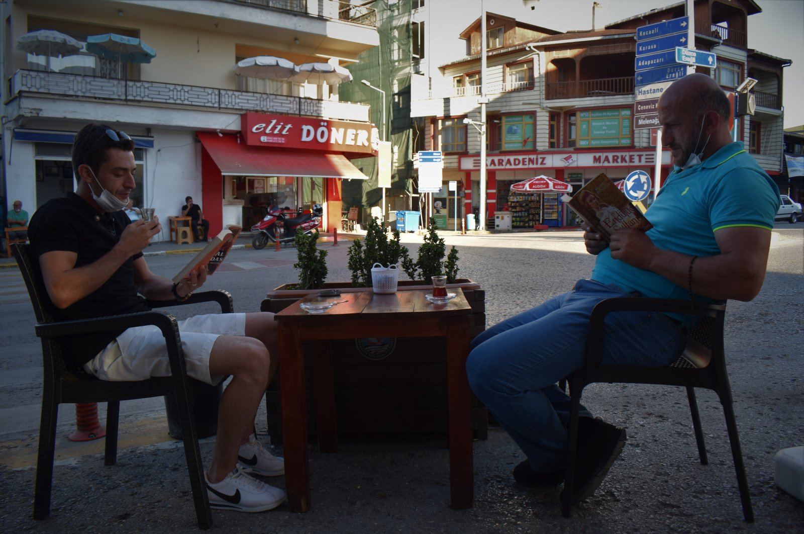 Two men read books at a table outside the coffeehouse in Akçakoca district, in Düzce, northern Turkey, Aug. 9, 2020. (AA Photo)