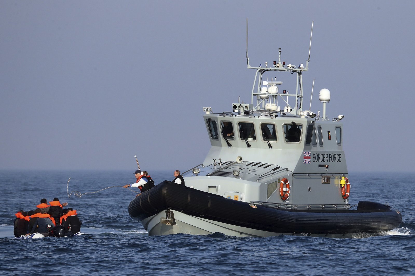 A Border Force vessel assists a group of people thought to be migrants traveling on an inflatable dinghy in the English Channel, Britain, Aug. 10, 2020. (AP Photo)