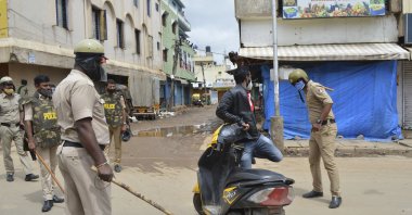 A policeman thrashes a motorist for violating prohibitory orders a day after violent protests in Bangalore, southern India, Aug. 12, 2020. (AP Photo)