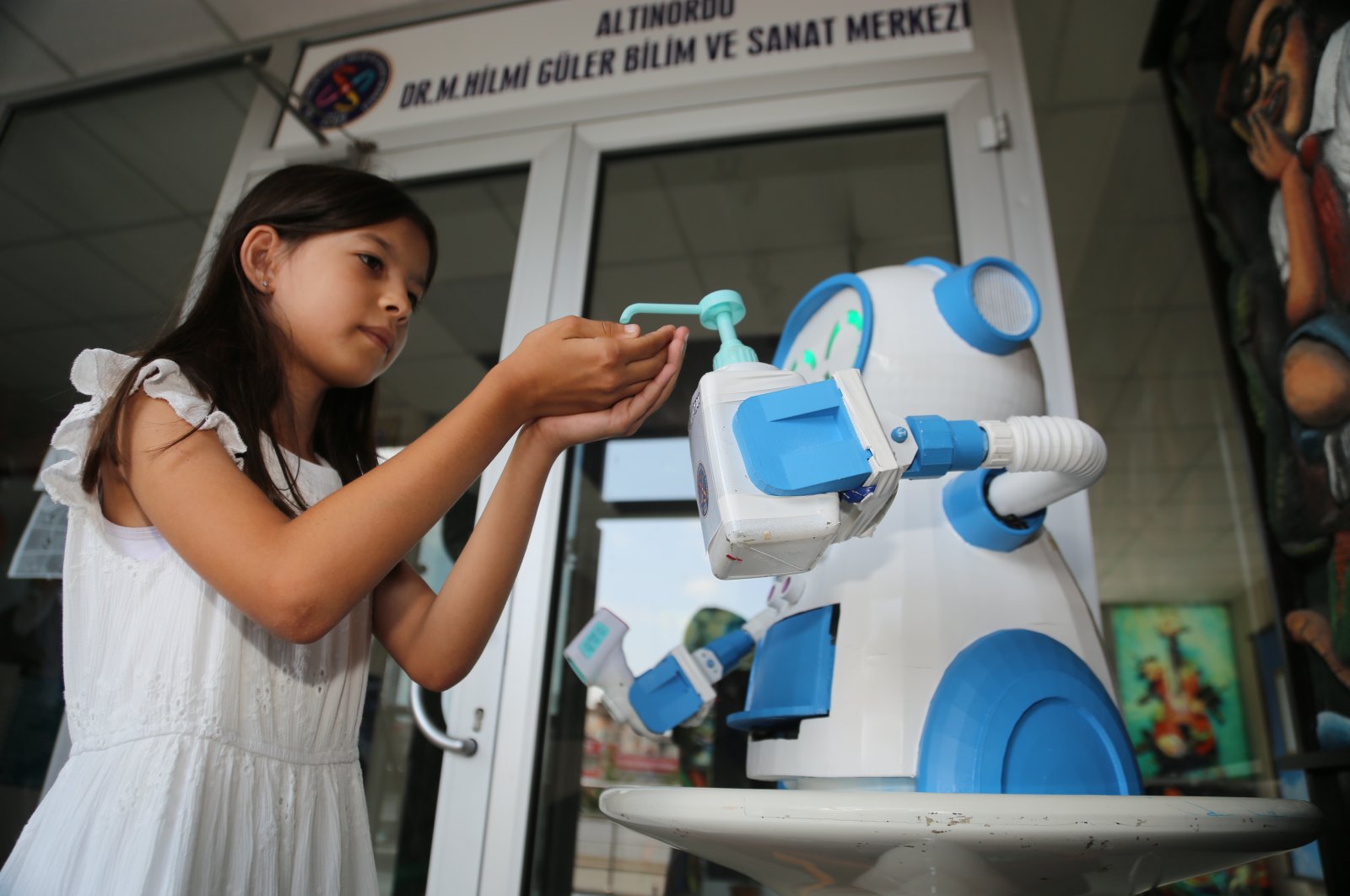 The robot pours disinfectant into the hand of a girl in Ordu, northern Turkey, Aug. 12, 2020. (AA Photo)