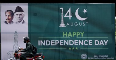 A vendor wearing a mask with the colors of Pakistan's national flag holds another mask while waiting for customers at a market in Karachi, Pakistan, Aug. 12, 2020. (AFP Photo)