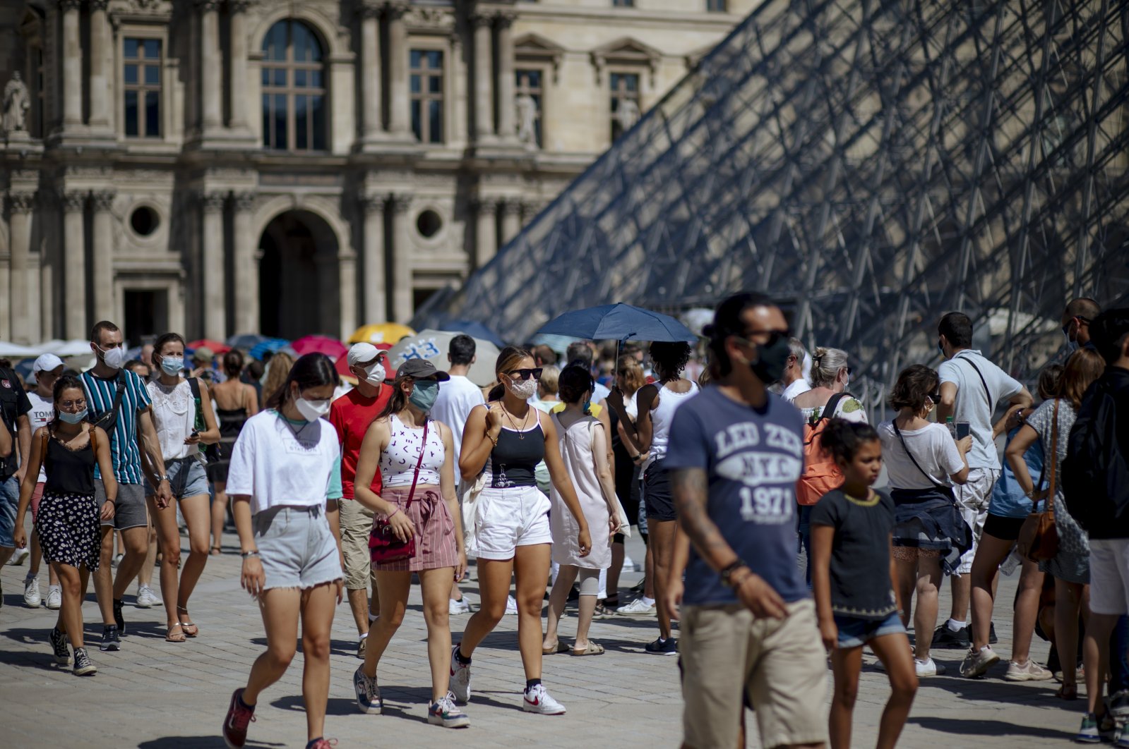People walk past the Louvre Museum in Paris, France, Aug. 12, 2020. (AP Photo)
