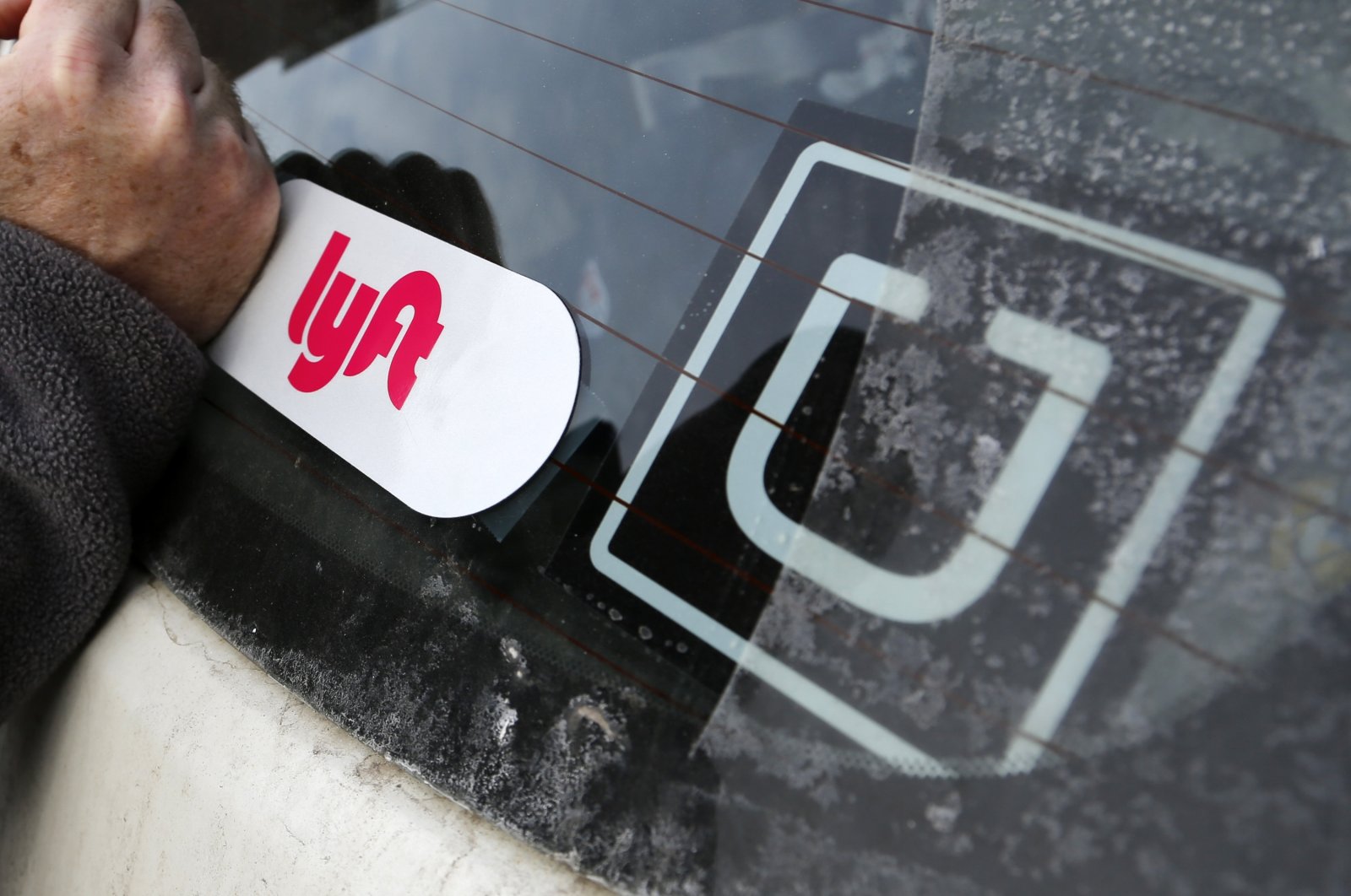 A Lyft logo is installed on a Lyft driver's car next to an Uber sticker in Pittsburgh, U.S., Jan. 31, 2018. (AP Photo)