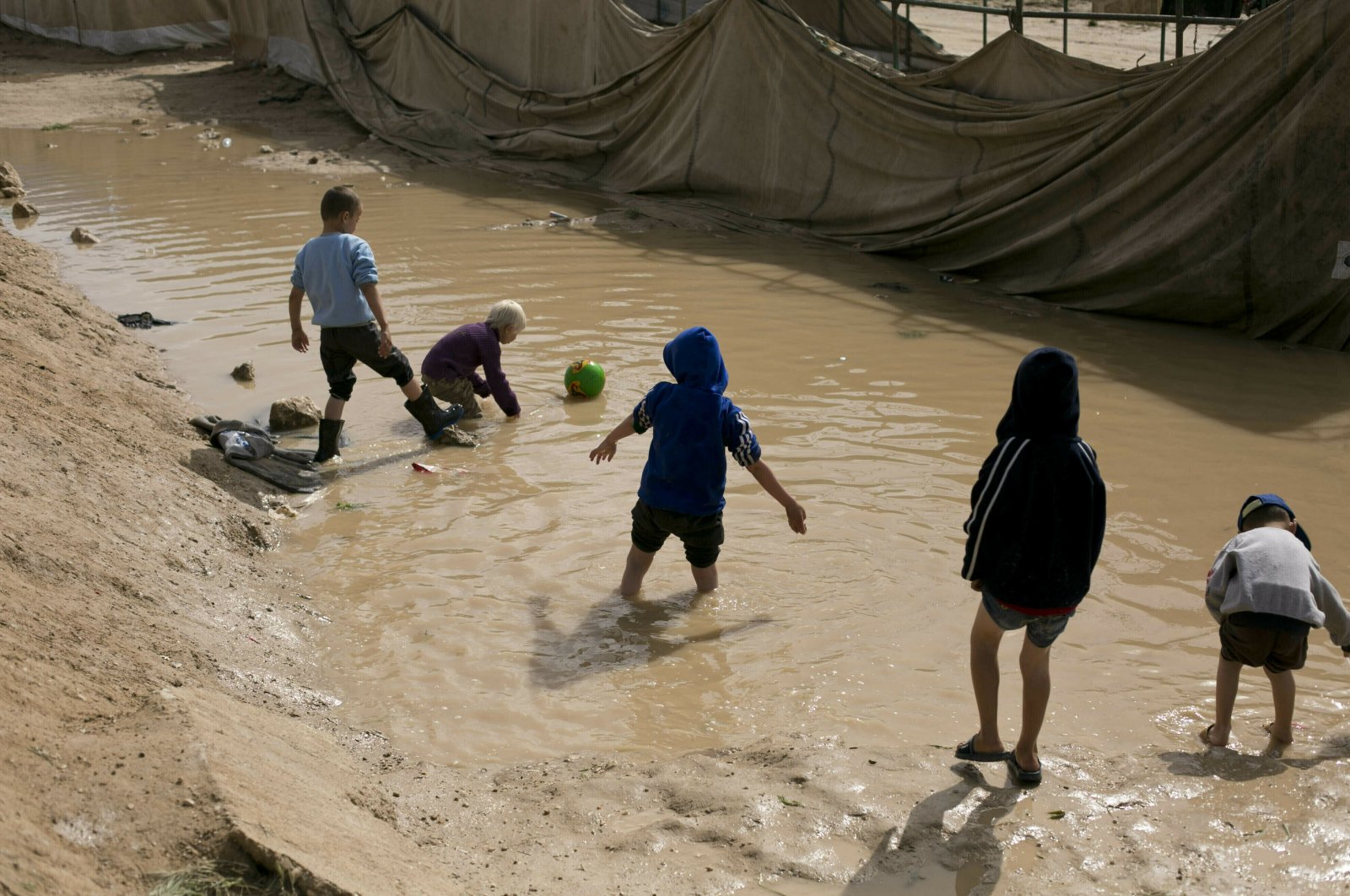 In this March 31, 2019 file photo, children play in a mud puddle in the section for foreign families at Al-Hol camp in Hasakeh province, Syria. (AP File Photo)