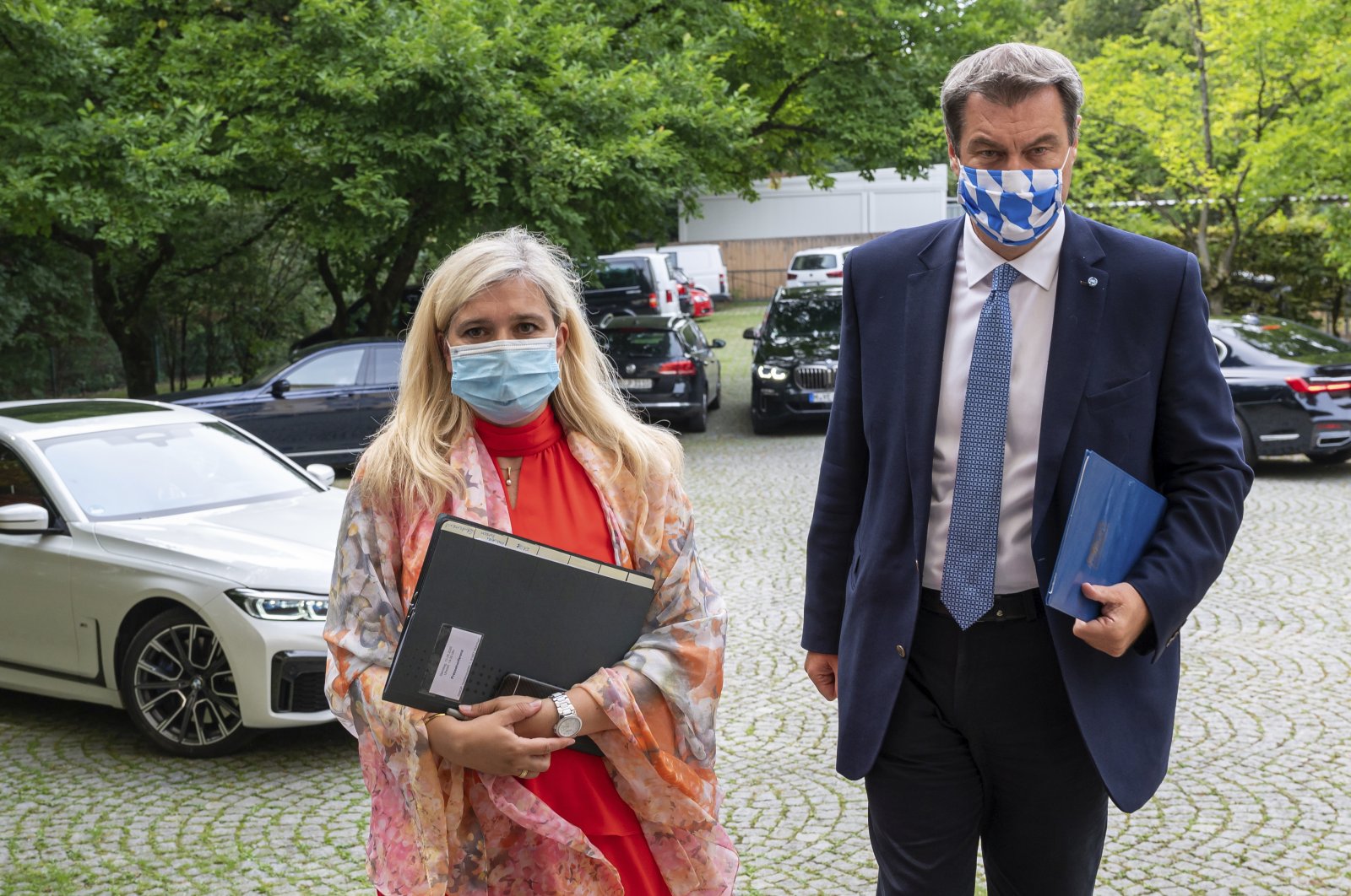Melanie Huml, Health Minister of the German state of Bavaria, left, and Bavaria's premier Markus Soeder, right, arrive for a joint press conference in Munich, Germany, Thursday, Aug. 13, 2020. (AP Photo)