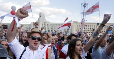 People with old Belarusian national flags shout during an opposition rally in front of the House of Government building in Minsk, Belarus, Aug. 16, 2020. (AP Photo)