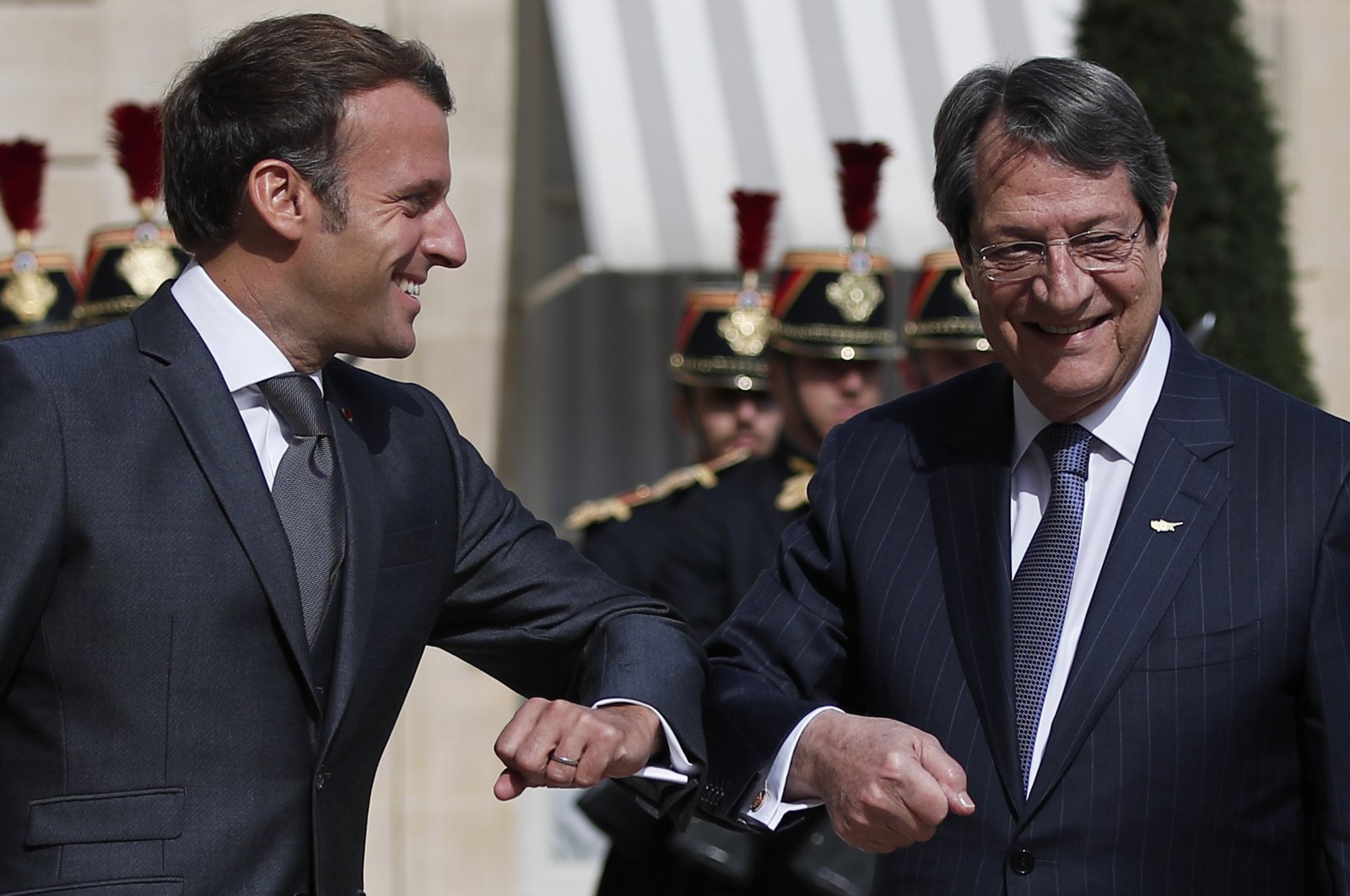 French President Emmanuel Macron, left, touches elbow as he welcomes Greek-Cypriot leader Nicos Anastasiades upon his arrival at the Elysee Palace, in Paris, Thursday, July 23, 2020. (AP Photo)