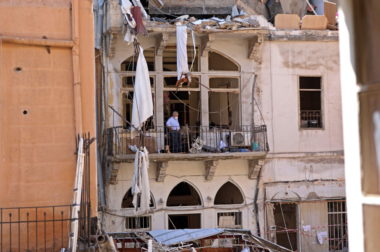 A man, clad in a mask due to the COVID-19 pandemic, stands amid debris on a balcony in the partially destroyed neighborhood of Mar Mikhael, Beirut, Lebanon, Aug. 14, 2020. (AFP Photo)
