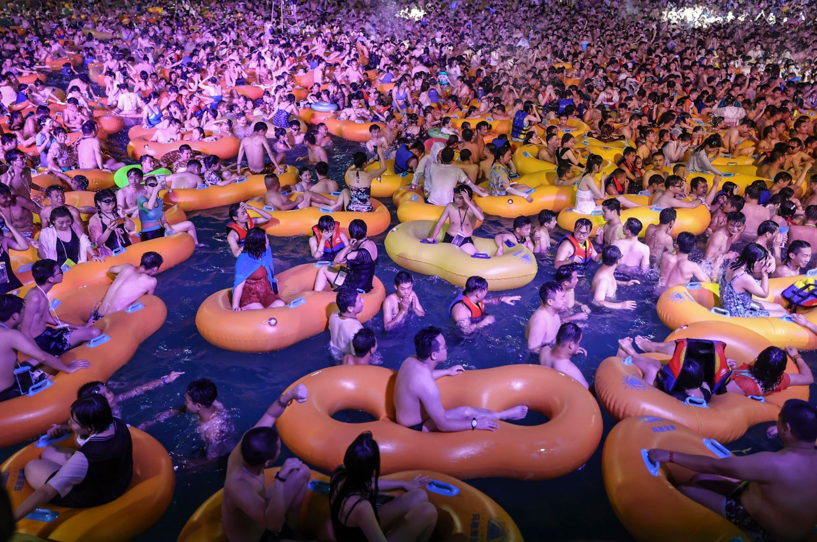 People watch a performance as they cool off in a swimming pool, Wuhan, China, Aug.15, 2020. (AFP Photo)