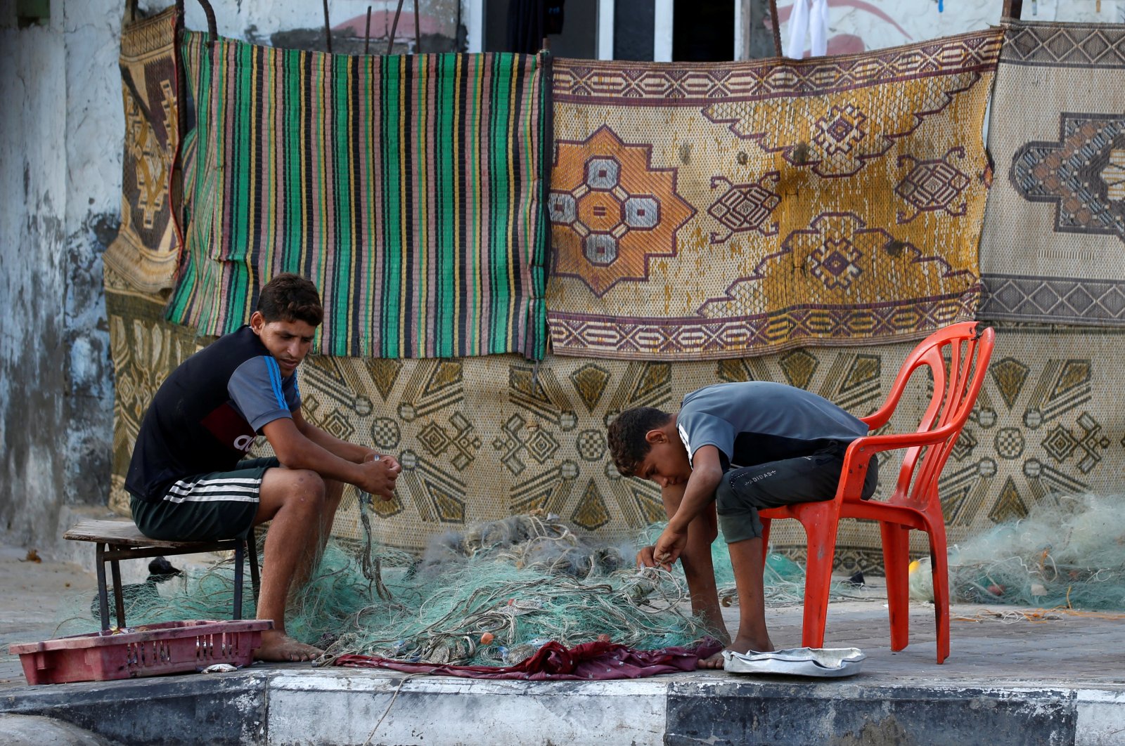 Boys fix a fishing net in the Beach refugee camp after Israel reduced the area where it permits Gazans to fish, Gaza City, Aug. 16, 2020. (REUTERS Photo)