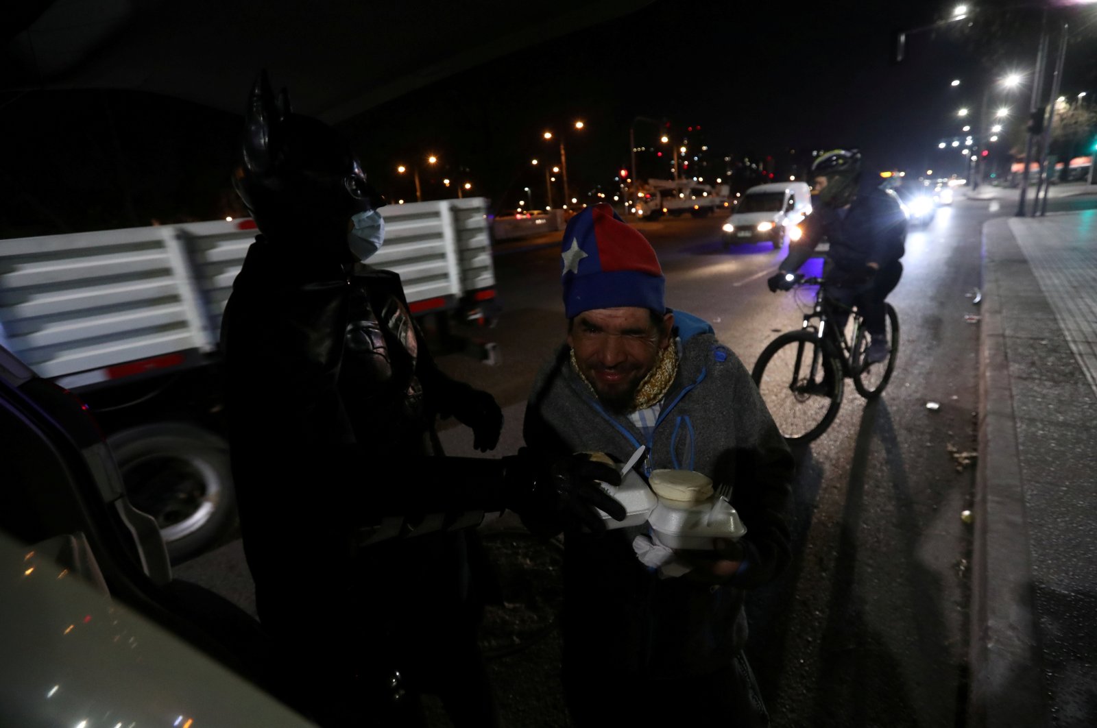 A homeless man gestures next to Chilean trader and so-called "Batman solidario" (Solidarity Batman), as he gives out charity food rations in the street, during the global outbreak of the coronavirus in Santiago, Chile, Aug. 12, 2020. (Reuters Photo)