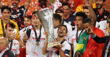 Sevilla's Spanish midfielder Jesus Navas holds the trophy as Sevilla's players celebrate  after winning the UEFA Europa League final football match Sevilla v Inter Milan on August 21, 2020, in Cologne, western Germany. (AFP Photo)