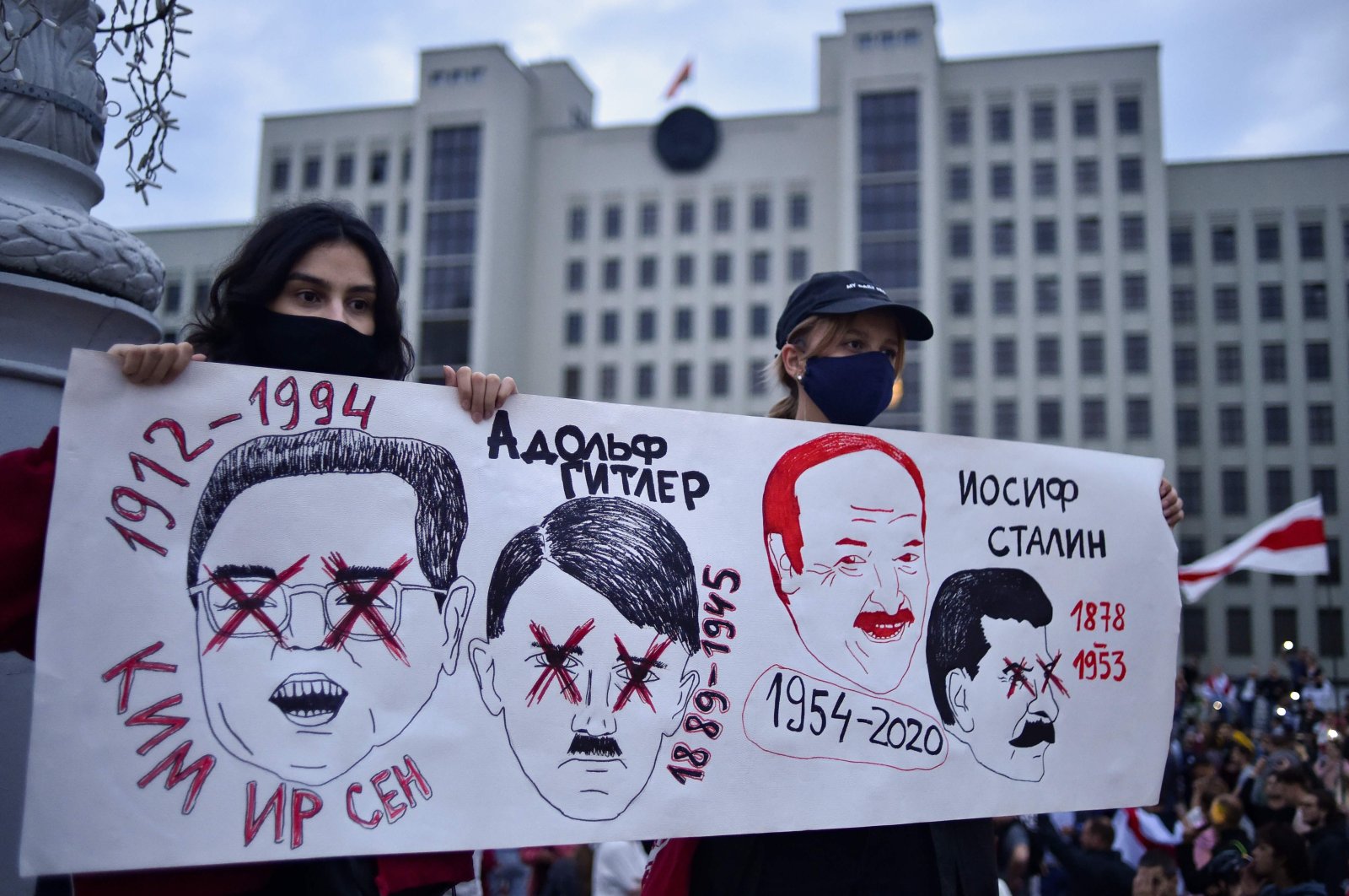 Women hold a placard with drawings of Kim Il Sung, Adolf Hitler, Alexander Lukashenko and Joseph Stalin during a rally to protest disputed presidential election results on Independence Square, Minsk, Belarus, Aug. 20, 2020. (AFP Photo)