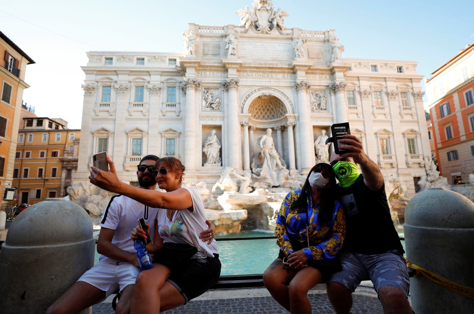 A couple wears face masks while other couple does not as they both take selfies in front of Rome's Trevi Fountain following a government decree that states face coverings must be worn between 6 p.m. and 6 a.m. in areas where gatherings are common, Aug. 19, 2020. (REUTERS Photo)
