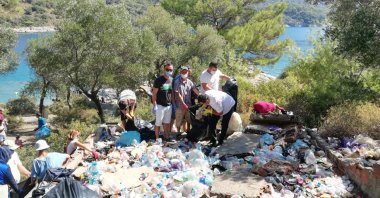 Volunteers stand beside a pile of collected garbage in Darboğaz Bay, in the Fethiye district of Muğla province, southwestern Turkey, Aug. 23, 2020. (AA Photo)