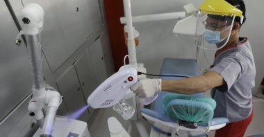 Gerry Aguilar uses a disinfecting gun to prevent the spread of COVID-19 as he cleans the room after each patient at a dental clinic in Manila, Philippines on July 6, 2020. (AP Photo)