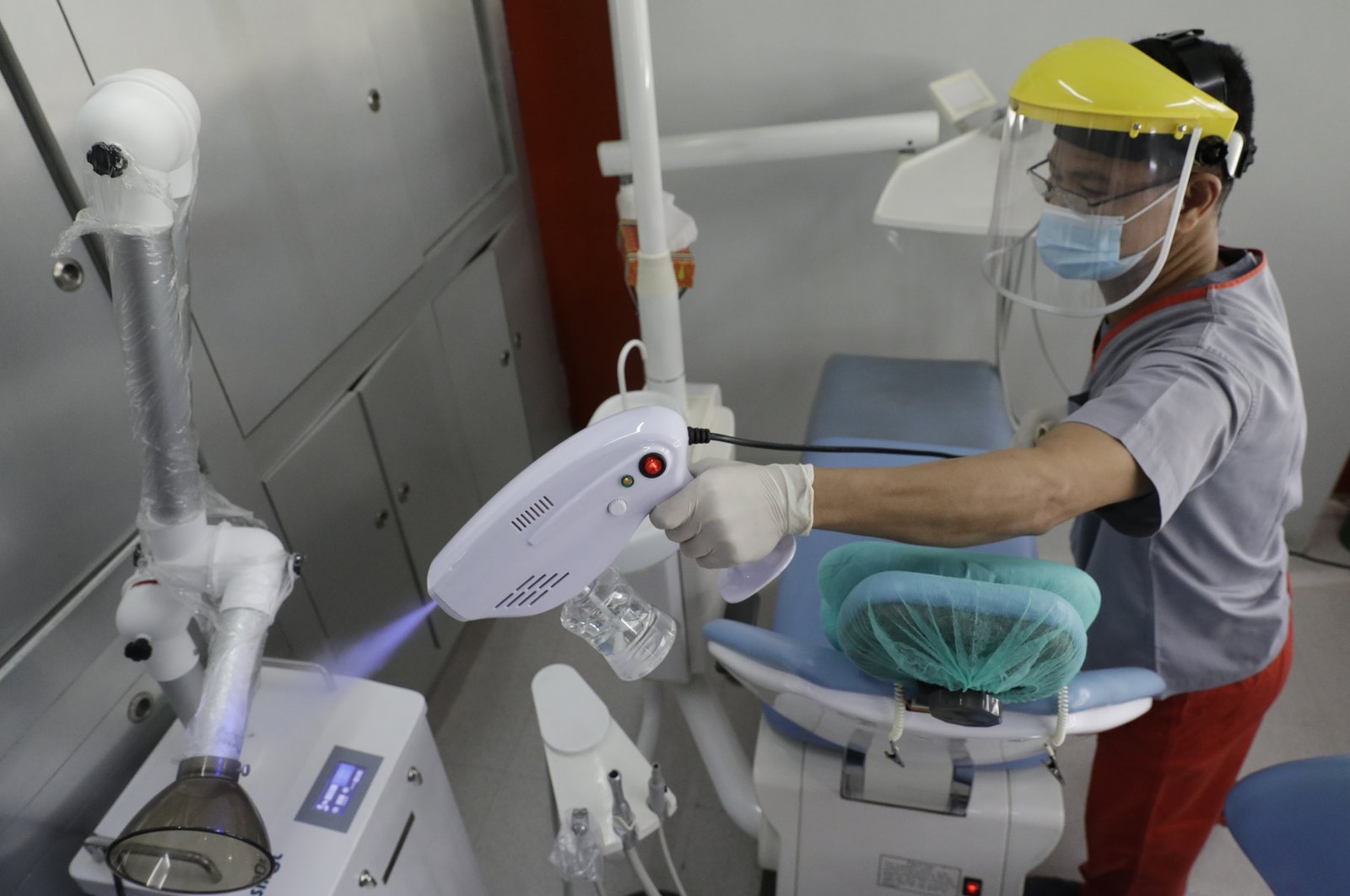 Gerry Aguilar uses a disinfecting gun to prevent the spread of COVID-19 as he cleans the room after each patient at a dental clinic in Manila, Philippines on July 6, 2020. (AP Photo)