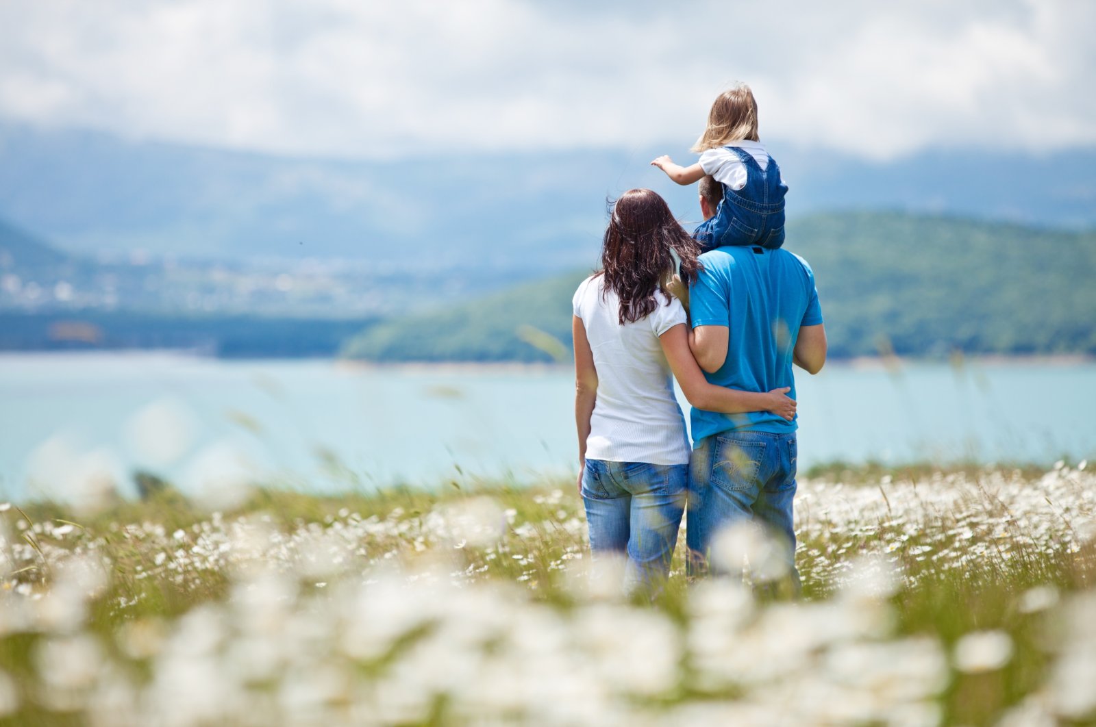A family standing in front of a lake watches nature (Shutterstock Photo)