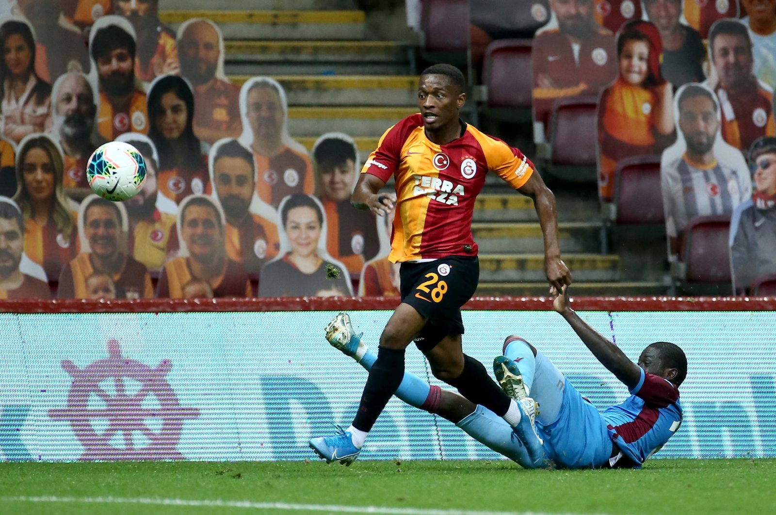 Fans' cut-outs appear in the background as Galatasaray's Jesse Sekidika (L) goes past Trabzonspor's Badou Ndiaye during a Turkish Süper Lig at the Türk Telekom Stadium, Istanbul, July 7, 2020 (AA Photo)