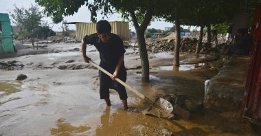 A flash flood-affected villager uses a shovel to clear the mud after heavy rains at Charikar in Parwan province on Aug. 26, 2020. (AFP Photo)