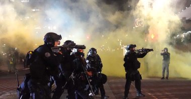 Portland police officers fire nonlethal rounds through smoke while dispersing protesters from Portland City Hall, Portland, Oregon, Aug. 25, 2020. (AFP Photo)