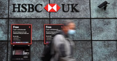 A pedestrian wearing a face mask or covering due to the COVID-19 pandemic walks past a branch of an HSBC bank in central London, Britain, Aug. 3, 2020. (AFP Photo)