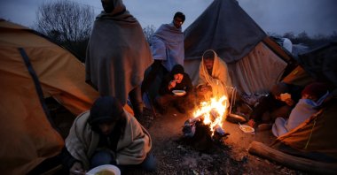 Migrants eat around a fire at a camp in Velika Kadusa, Bosnia-Herzegovina, close to the border with Croatia, Nov. 18, 2019. (AP Photo)