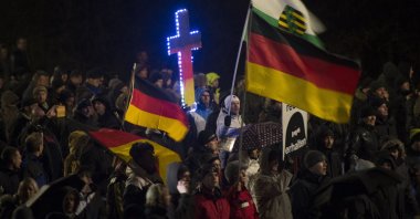 A demonstrator holds a crucifix in the colors of Germany during a rally by a mounting right-wing populist movement called PEGIDA on Jan. 5, 2015, in Dresden. (AFP Photo)
