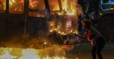 A protester lights a cigarette on a garbage truck that was set on fire during protests in Kenosha, Aug. 24, 2020.(AP Photo)