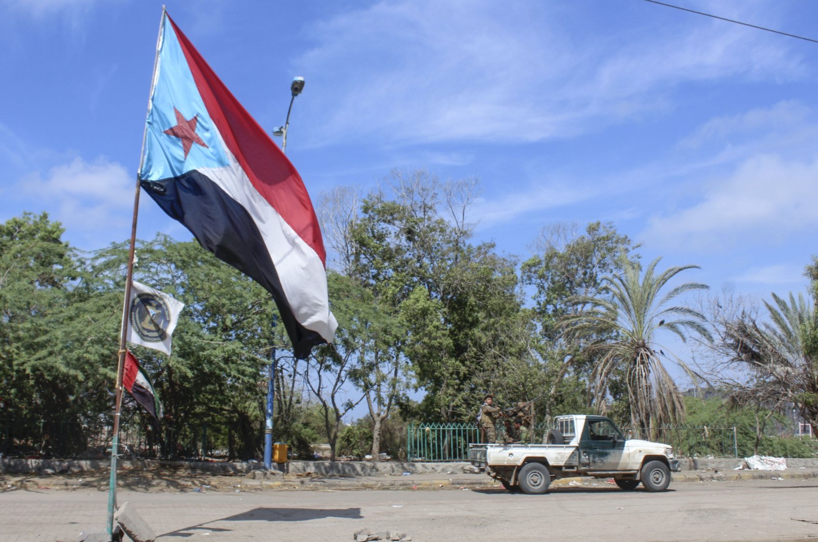 Fighters with Yemen's Southern Transitional Council (STC) drive a vehicle past a separatist flag (the old flag of South Yemen) as they deploy in the southern city of Aden, April 26, 2020. (AFP Photo)