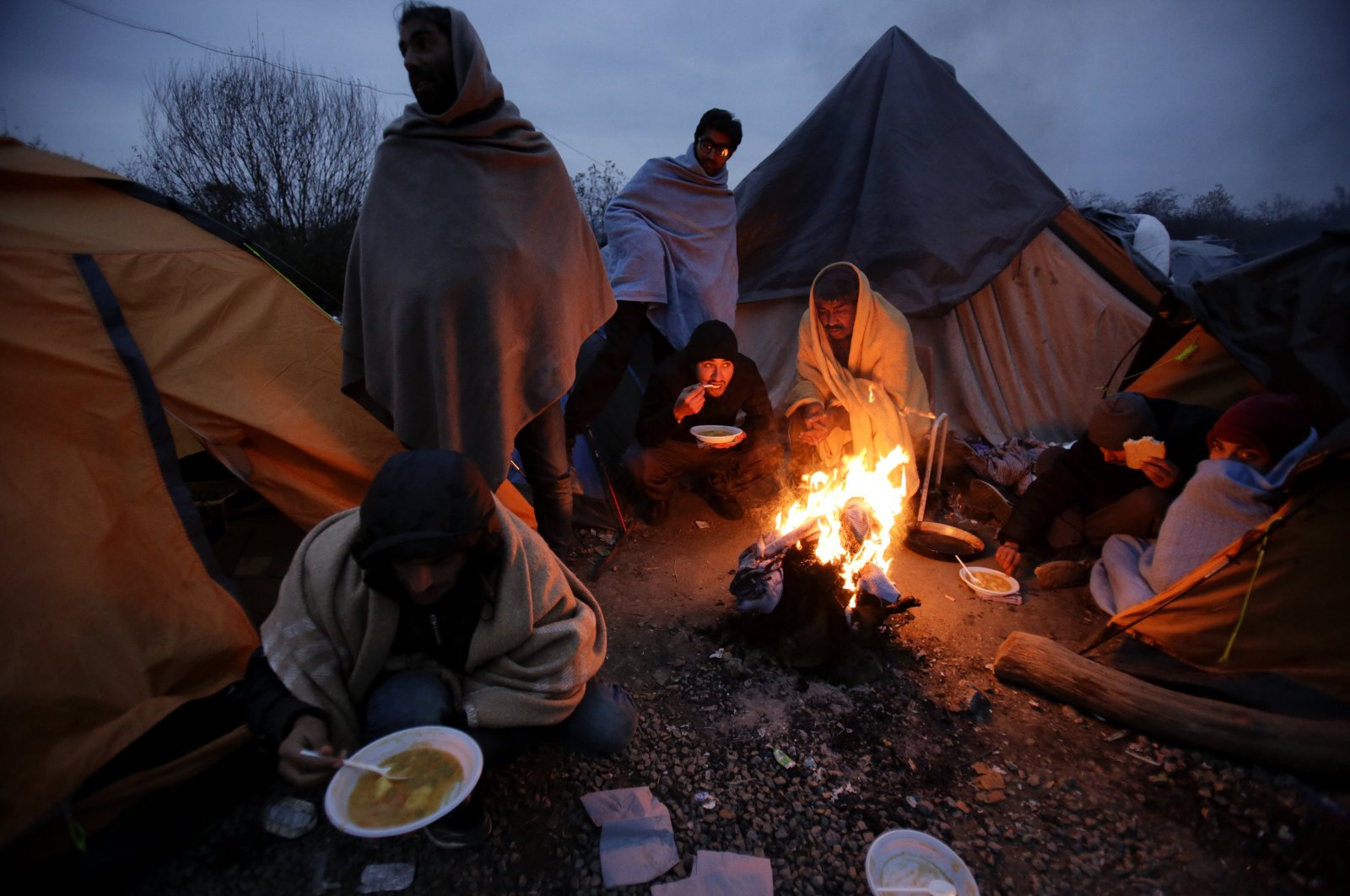 Migrants eat around a fire at a camp in Velika Kadusa, Bosnia-Herzegovina, close to the border with Croatia, Nov. 18, 2019. (AP Photo)