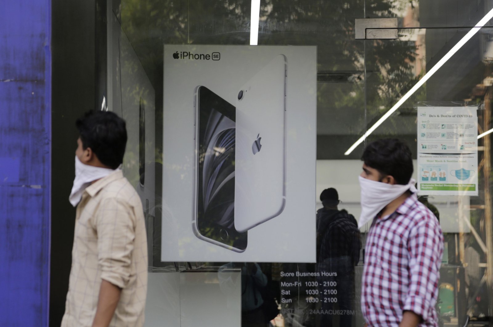 People walk past an image of an iPhone displayed at an Apple store in Ahmedabad, India, Saturday, Aug. 1, 2020. (AP Photo)