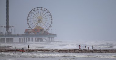 People walk along a jetty as waves roll in from approaching Hurricane Laura in Galveston, Texas,  Aug. 25, 2020. (AFP Photo)