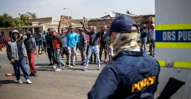 A member of the South African Police Service (SAPS) watch as residents protest outside the SAPS offices in Eldorado Park, Johannesburg, Aug. 27, 2020. (AFP Photo)