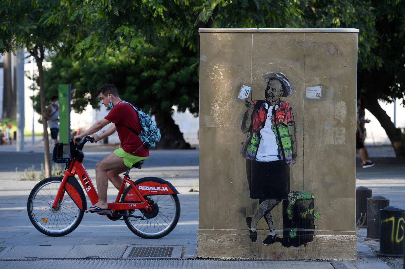A man rides a bicycle past street art by TVBoy titled "Viajando como un Rey" (Travelling like a King) depicting former Spanish King Juan Carlos, in Barcelona, Spain, Aug. 20, 2020. (Photo by Josep Lago via AFP)
