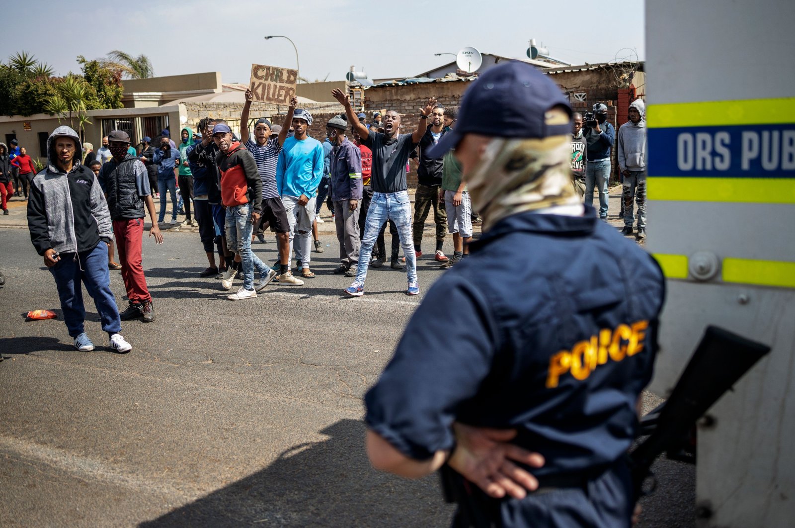 A member of the South African Police Service (SAPS) watch as residents protest outside the SAPS offices in Eldorado Park, Johannesburg, Aug. 27, 2020. (AFP Photo)