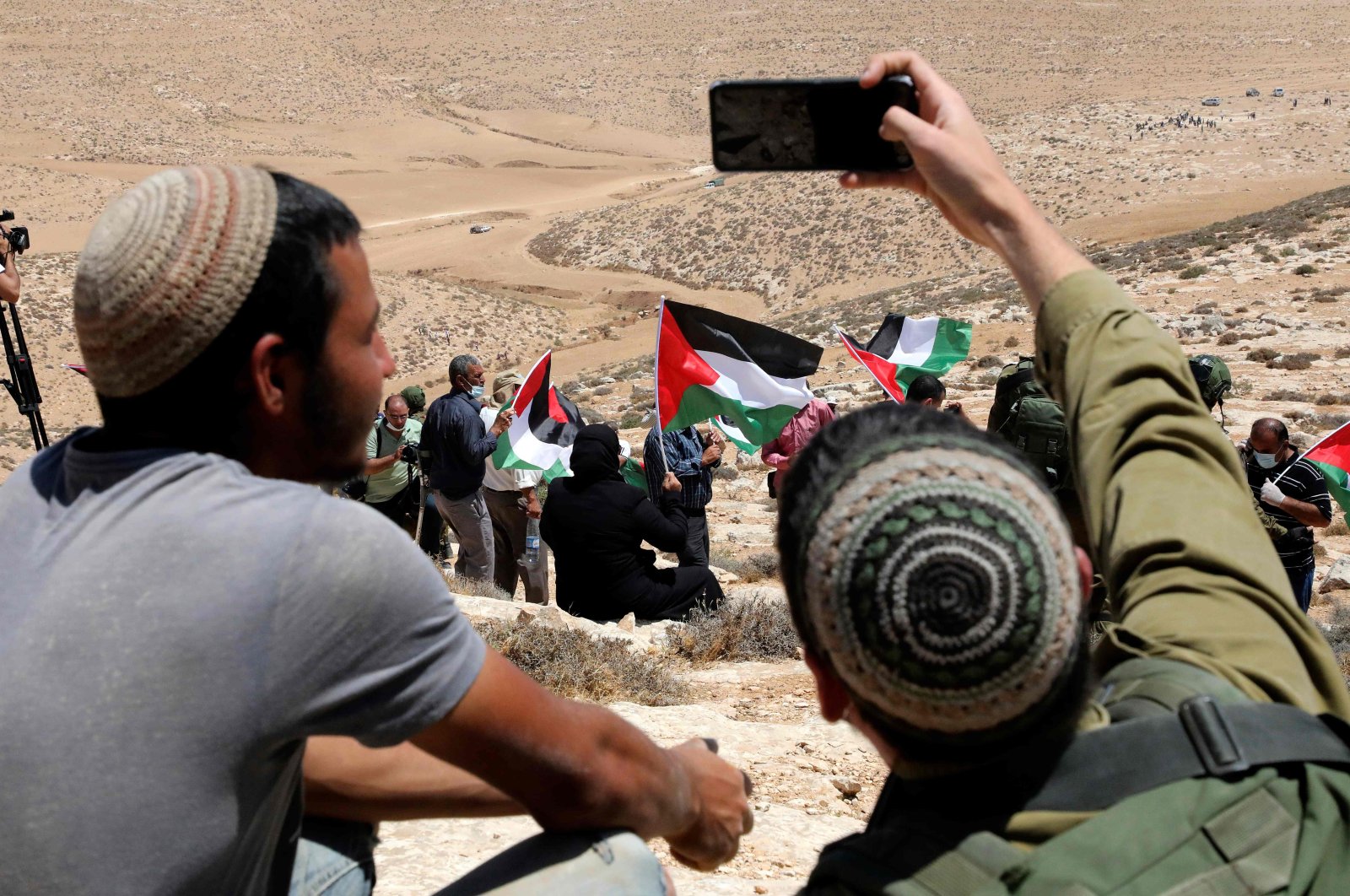 An Israeli soldier takes a selfie of himself with a Jewish settler, as Palestinian landowners and demonstrators protest Israeli settlement building activities on their land in al-Thaalaba village, near Yatta, south of Hebron city in the occupied West Bank, Aug. 21, 2020. (AFP Photo)