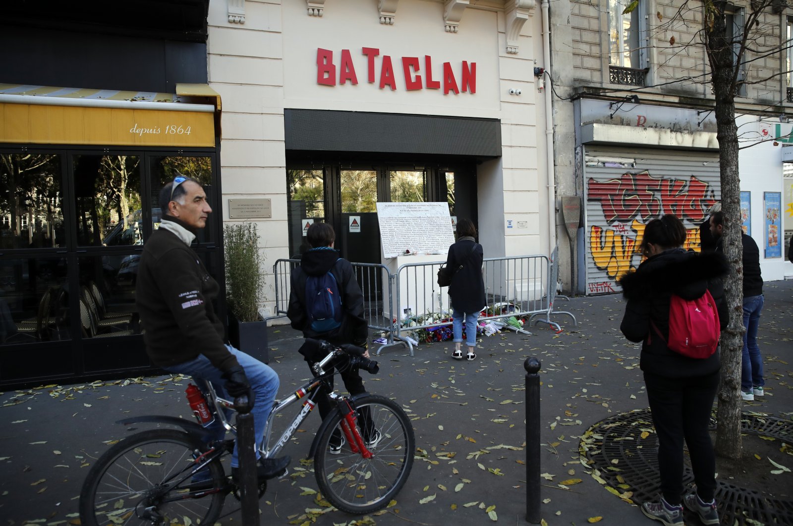 People stand in front of the entrance of the Bataclan concert hall after a ceremony marking the third anniversary of the Paris attacks of November 2015 in which 130 people were killed, in Paris, France, Nov. 13, 2018. (AP Photo)