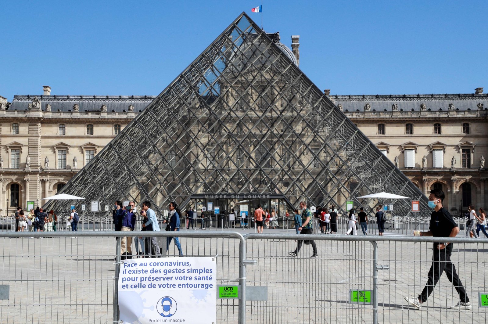 People wearing face masks walk in front of the Louvre Pyramid, Paris, France, Aug. 27, 2020. (AFP Photo)