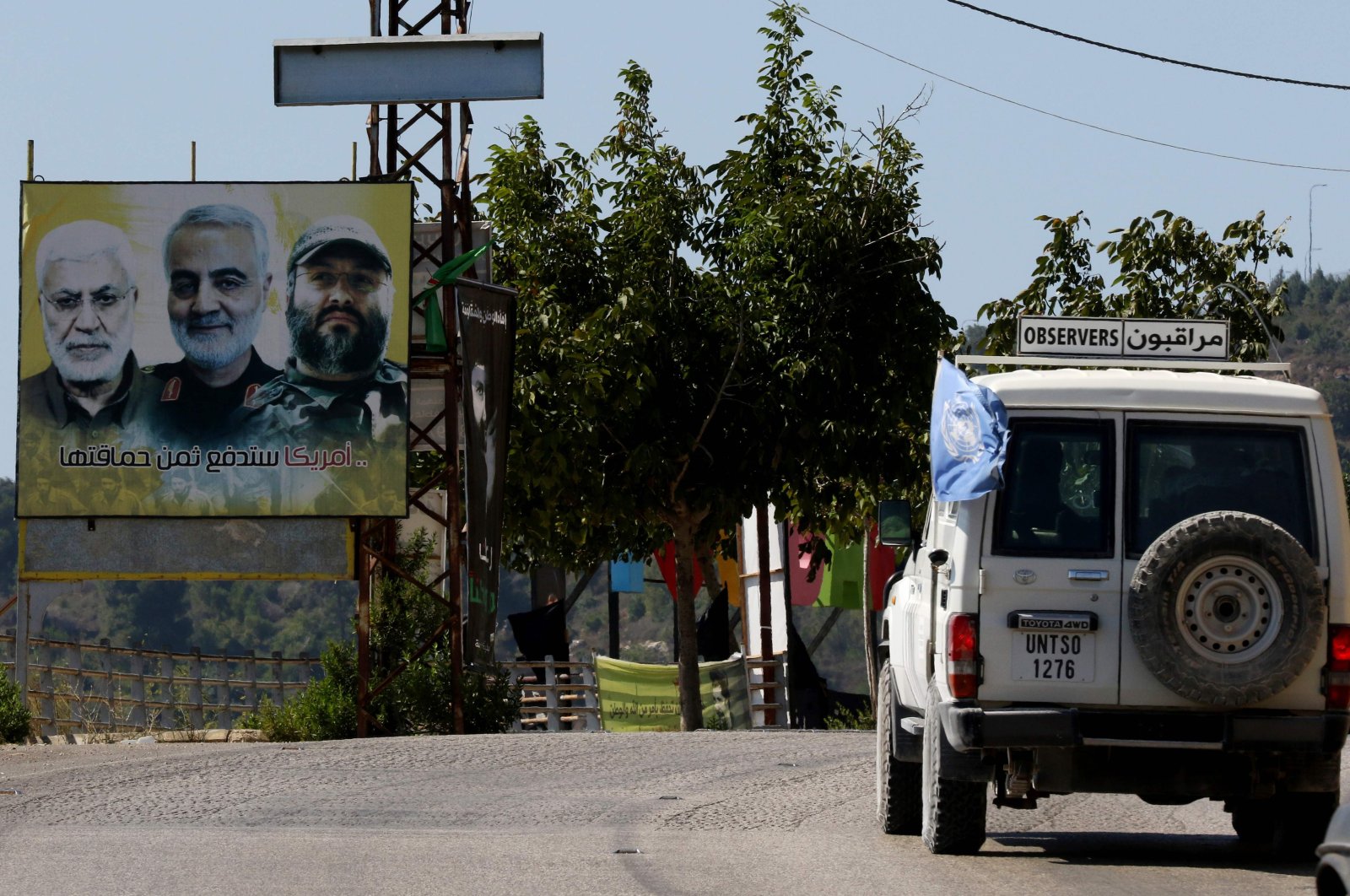 A UNIFIL patrol drives past a billboard showing the faces of slain Iraqi Hashed al-Shaabi (Popular Mobilisation) forces commander Abu Mahdi al-Muhandis (L), Iranian Quds Force commander Qasem Soleimani (C) and Hezbollah commander Imad Mughniyeh (R), in the southern Lebanese village of Adaisseh on the border with Israel, Aug. 26, 2020. (AFP Photo)