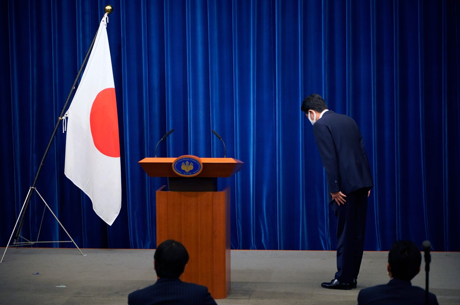Japanese Prime Minister Shinzo Abe bows to the national flag at the start of a press conference at the prime minister official residence in Tokyo, Aug. 28, 2020. (AFP Photo)