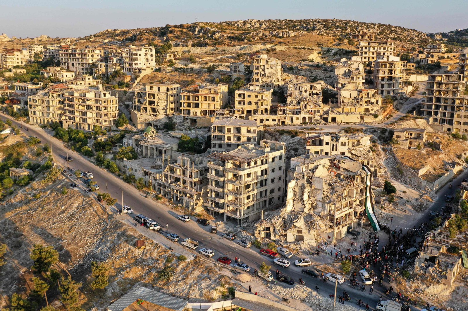 An aerial view of Syrians gathering for a demonstration by the ruins of a building that was hit in a prior bombardment and adorned with a giant flag of the Syrian opposition, in the town of Ariha in opposition-held northwestern Idlib province, Syria, Aug. 28, 2020. (AFP Photo)