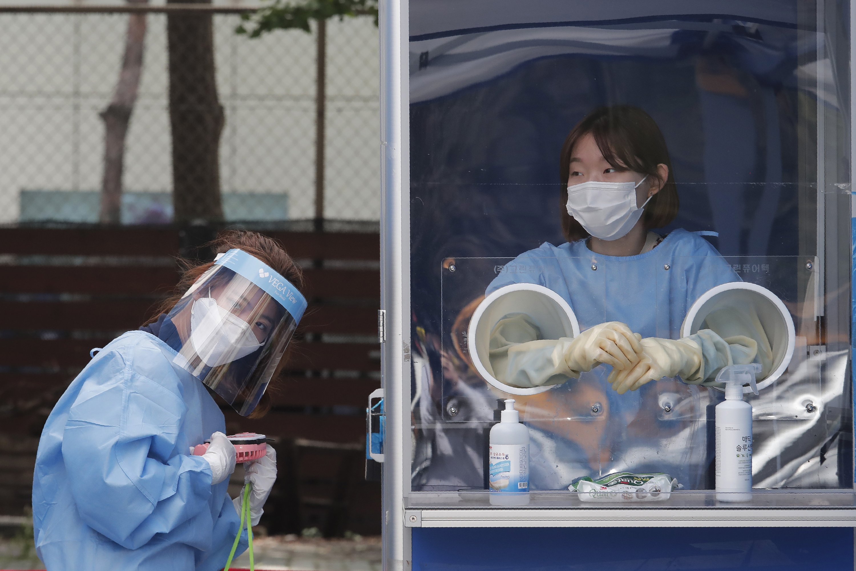 A medical worker holds a portable fan during the sweltering heat while police officers are tested for COVID-19 at a makeshift clinic in Seoul, South Korea, Aug. 19, 2020. (AP Photo)