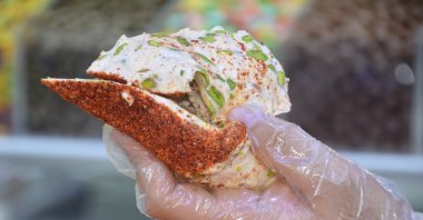 A man extends a sweet and spicy creation produced by confectioner Ökkeş Nagaş in Kahramanmaraş, southern Turkey, Aug. 25, 2020. (AA Photo)