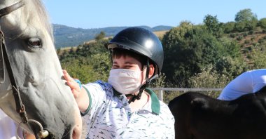 A boy caresses a horse at the ranch, in the Serdivan district of Sakarya province, northwestern Turkey, Sept. 1, 2020. (AA Photo)