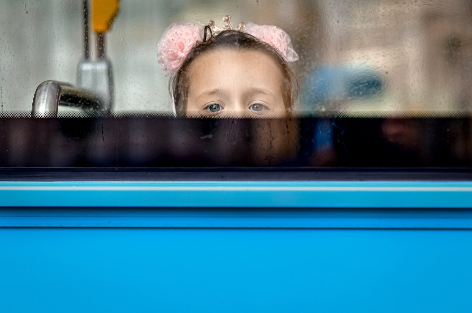 A little girl peers from behind a window bus upon arriving with kindergarten colleagues for a day of joint activities in Bucharest, Romania, Wednesday, Aug. 19, 2020. (AP Photo)