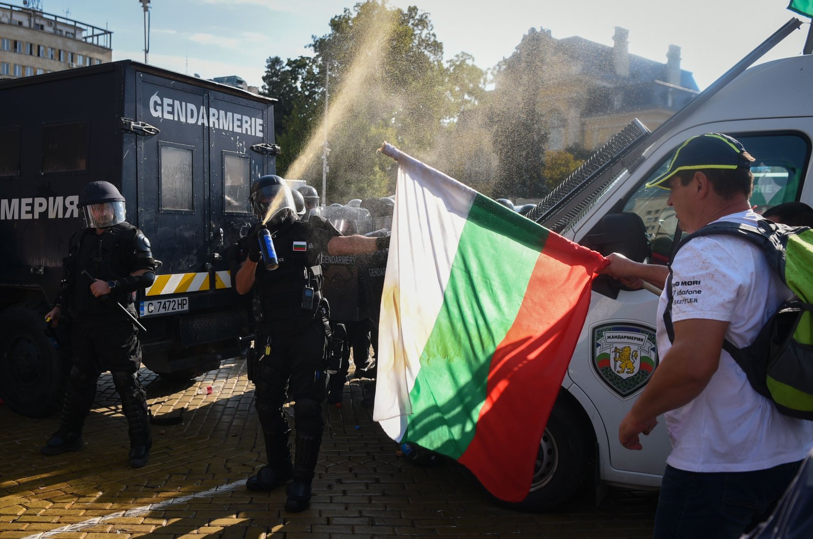 A police officer uses pepper spray in front of a man holding a Bulgarian national flag, as clashes erupt during an anti-government demonstration while parliament discusses changing the constitution, Sofia, Bulgaria, Sept. 2, 2020. (AFP Photo)